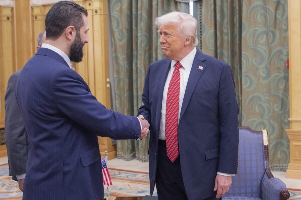 In this photo released by the Saudi Royal Palace, President Donald Trump, right, shakes hands with Syria's interim President Ahmad al-Sharaa, in Riyadh, Saudi Arabia, Wednesday, May 14, 2025. (Bandar Aljaloud/Saudi Royal Palace via AP)