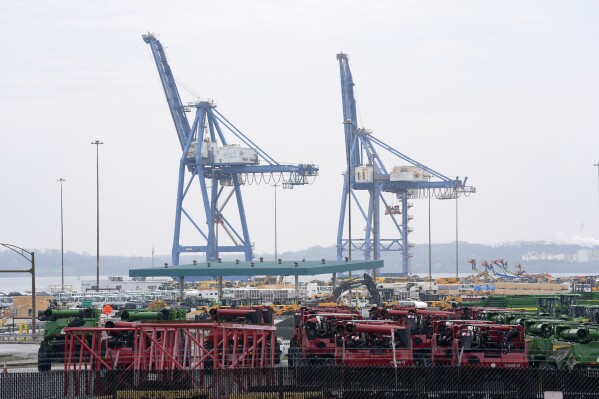 Cranes stand idle above farm equipment on Thursday, March 28, 2024, in Dundalk, Md. The deadly collapse of the historic Francis Scott Key Bridge has shaken Baltimore to its core and challenged its cultural identity as a port city that dates back to before the U.S. declared its independence. (AP Photo/Matt Rourke)