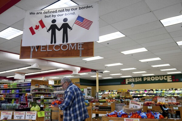 A shopper at the Point Roberts International Marketplace inspects a bag of oranges Tuesday, March 18, 2025, in Point Roberts, Wash. (AP Photo/Lindsey Wasson)