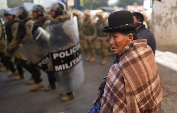A woman observes military police patrolling after police spent days clearing roadblocks set up by supporters of Bolivia's former President Evo Morales who want him to be able to run for president again in Llallagua, Bolivia, Friday, June 13, 2025. (AP Photo/Juan Karita)