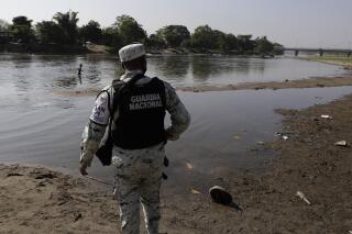 FILE - In this March 21, 2021 file photo, a Mexican National Guard stands on the bank of the Suchiate River, the natural border with Guatemala and Mexico, near Ciudad Hidalgo, Mexico, as part of an operation on Mexico's southern border to crack down on migrant smuggling. President Andrés Manuel López Obrador said on Tuesday, June 15, 2021, he plans to make the National Guard part of the army, after it was created as a civilian-controlled force two years prior. (AP Photo/Eduardo Verdugo, File)