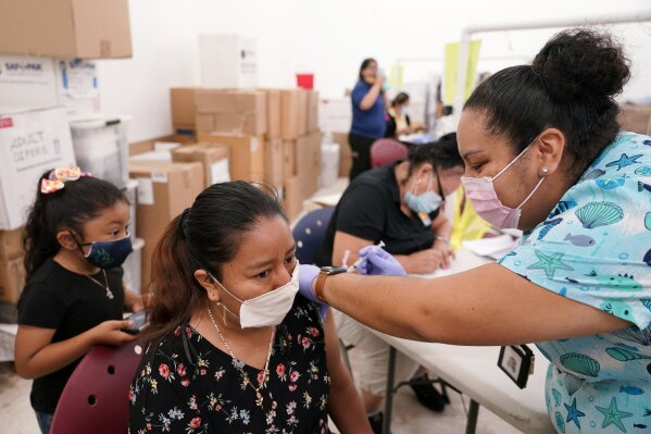 FILE - In this April 10, 2021, file photo, registered nurse Ashleigh Velasco, right, administers the Johnson & Johnson COVID-19 vaccine to Olga Perez at a clinic held by Healthcare Network, in Immokalee, Fla. With coronavirus shots now in the arms of nearly half of American adults, the parts of the U.S. that are excelling and those that are struggling with vaccinations are starting to look like the nation’s political map: deeply divided between red and blue states. (AP Photo/Lynne Sladky, File)