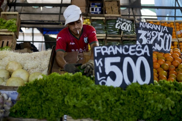 A vendor arranges vegetables at a market on the outskirts of Buenos Aires, Argentina, Wednesday, Jan. 10, 2024. The price for lettuce reads 500 Argentine pesos per kilogram, or about .60 US cents. (AP Photo/Natacha Pisarenko)