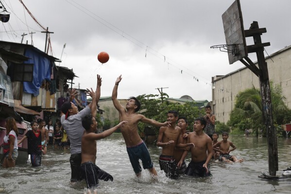 FILE - Filipino boys play basketball in floodwaters from a swollen creek at a coastal village in Malabon, north of Manila, Philippines, Wednesday, July 8, 2015. (AP Photo/Aaron Favila, File)