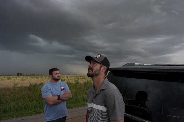 Victor Gensini, Northern Illinois University meteorology professor and a lead scientist of Project ICECHIP, right, and Logan Bundy, PhD Candidate at NIU and ICECHIP IOP assistant, look at cloud formations during a Project ICECHIP operation, Tuesday, June 3, 2025, south of Tipton, Okla. (AP Photo/Carolyn Kaster)