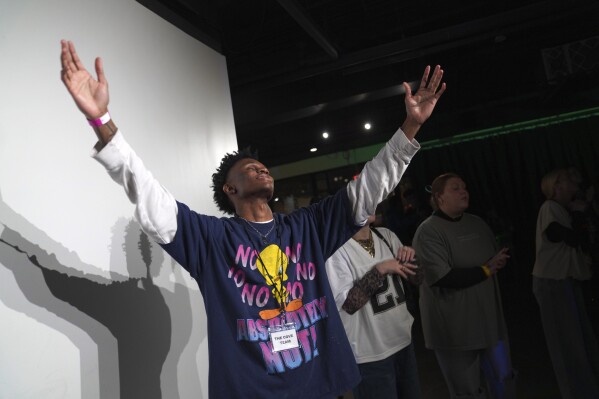 Jeremiah Manley, left, and other attendees at The Cove, an 18-and-up, pop-up Christian nightclub, raise their arms in worship on Saturday, Feb. 17, 2024, in Nashville, Tenn. The Cove was started last year by seven Black Christian men in their 20s who sought to build a thriving community and a welcoming space for young adults outside houses of worship. (APPhoto/Jessie Wardarski)