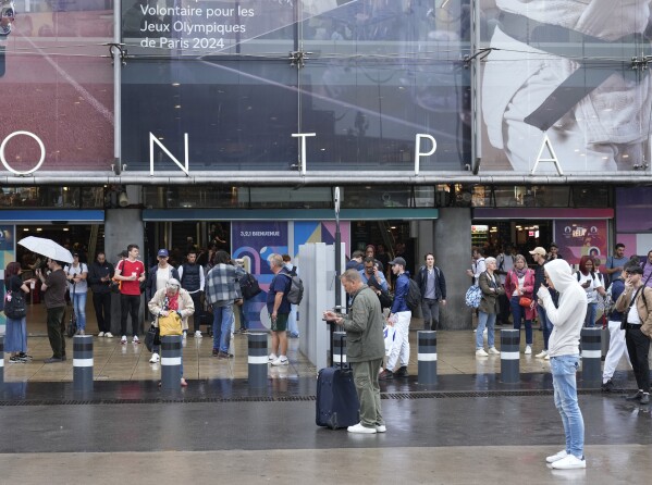 Travelers wait outside the Gare de Montparnasse train station, at the 2024 Summer Olympics, Friday, July 26, 2024, in Paris, France. (AP Photo/Yasin Dar)