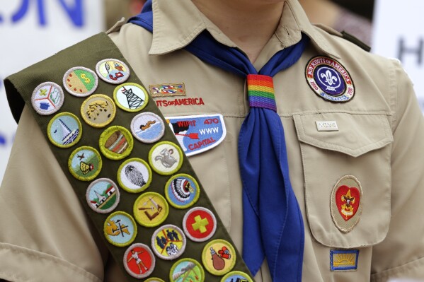 FILE - Merit badges and a rainbow-colored neckerchief slider are affixed on a Boy Scout uniform outside the headquarters of Amazon in Seattle. The U.S. organization, which now welcomes girls into the program and allows them to work toward the coveted Eagle Scout rank, announced Tuesday, May 7, 2024, that it will change its name to Scouting America as it focuses on inclusion. (AP Photo/Ted S. Warren, File)