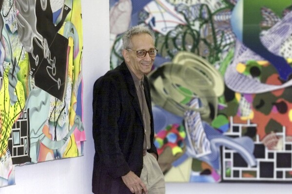 FILE - U.S. artist Frank Stella stands between his collages "Die Marquise von O..." (The Marchioness of O...), left, and "Die Verlobung in St. Domingo" (The Engagement in St. Domingo") at the Wuerttembergischer Kunstverein Stuttgart, the gallery of the German Federal state of Baden-Wuerttemberg, in Stuttgart, southwestern Germany, Sept. 20, 2001. Stella, a painter, sculptor and printmaker whose constantly evolving works are hailed as landmarks of the minimalist and post-painterly abstraction art movements, died Saturday, May 4, 2024, at his home in Manhattan. He was 87. (AP Photo/Thomas Kienzle, File)