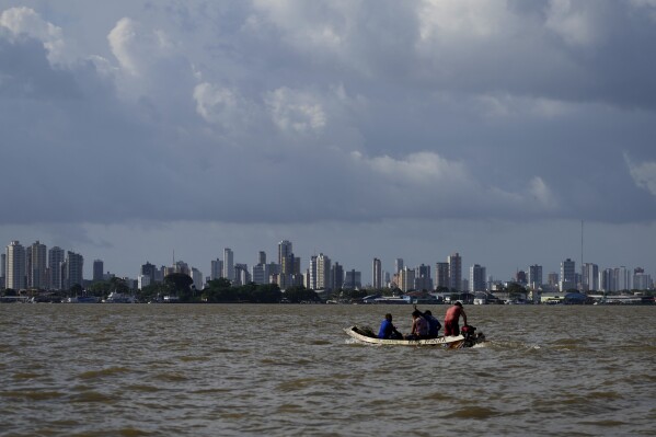 Um barco navega na baía do Rio Guamá com Belém, Brasil, ao fundo, 6 de agosto de 2023. (AP Photo/Eraldo Peres)