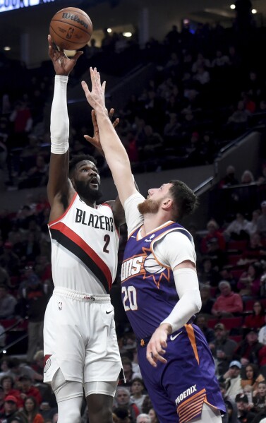 Portland Trail Blazers center Deandre Ayton, left, shoots over Phoenix Suns center Jusuf Nurkic during the second half of an NBA basketball game in Portland, Ore., Tuesday, Dec. 19, 2023. The Blazers won 109-104. (AP Photo/Steve Dykes)