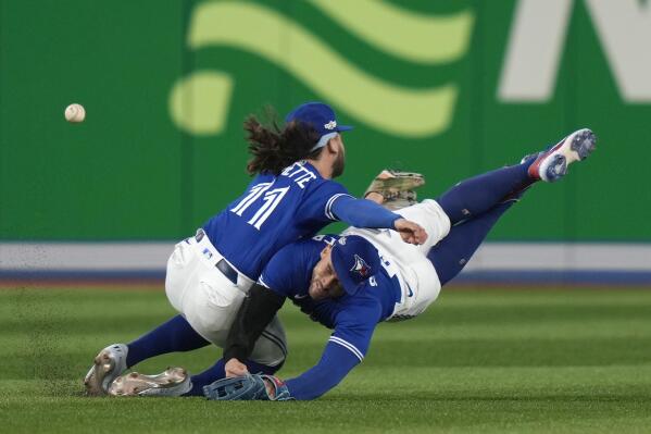 Toronto Blue Jays shortstop Bo Bichette (11) and center fielder George Springer (4) collide while to trying to catch a three-RBI double off the bat of Seattle Mariners shortstop J.P. Crawford during  the eighth inning of Game 2 of a baseball AL wild-card playoff series, Saturday, Oct. 8, 2022, in Toronto. (Frank Gunn/The Canadian Press via AP)