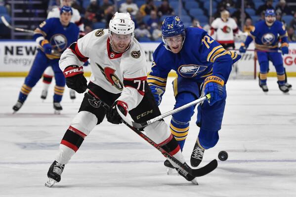 Ottawa Senators center Chris Tierney, left, flips the puck forward while pressured by Buffalo Sabres right wing Tage Thompson during the first period of an NHL hockey game in Buffalo, N.Y., Thursday, Feb. 17, 2022. (AP Photo/Adrian Kraus)