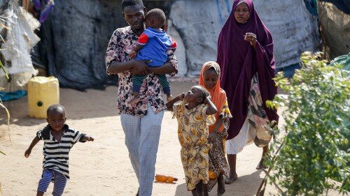 Abdikadir Omar walks to a shelter with his wife and children, who made a 12-day journey from Somalia in search of food and safety, to Dadaab refugee camp in northern Kenya, Thursday, July 13, 2023. One of the world's largest refugee camps offers a stark example of the global food security crisis with thousands of people fleeing Somalia in recent months to escape drought and extremism but finding little to eat when they arrive at the Dadaab camp in neighboring Kenya. (AP Photo/Brian Inganga)