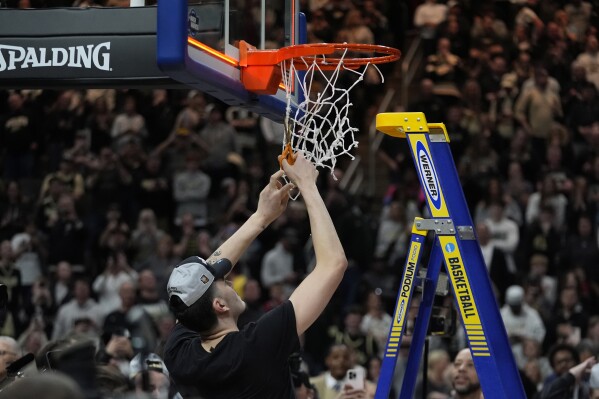 Purdue center Zach Edey helps cut down the net after the second half of an Elite Eight college basketball game against Tennessee in the NCAA Tournament, Sunday, March 31, 2024, in Detroit. (AP Photo/Paul Sancya)