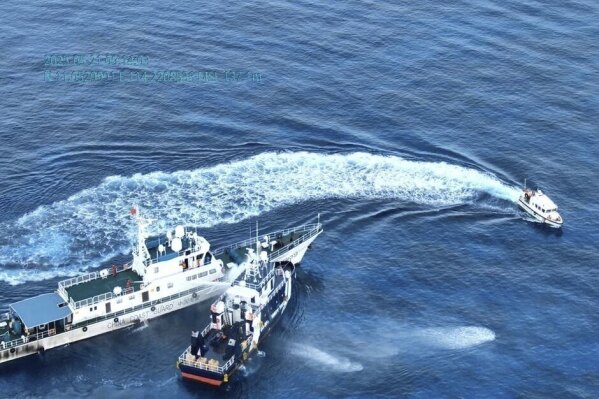 In this handout photo grabbed from video provided by the Philippine Coast Guard/Bureau of Fisheries and Aquatic Resources (PCG/BFAR), a Chinese Coast Guard ship, left, uses water cannon and sideswipped a Philippine fisheries vessel on a research mission near one of three sandbars called Sandy Cay in the disputed South China Sea on Wednesday May 21, 2025. (PCG/BFAR via AP)