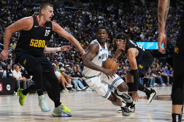 Minnesota Timberwolves guard Anthony Edwards, center, drives to the basket between Denver Nuggets center Nikola Jokic, left, and forward Aaron Gordon in the second half of Game 7 of an NBA second-round playoff series Sunday, May 19, 2024, in Denver. (AP Photo/David Zalubowski)