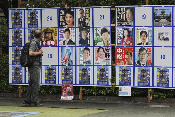 A person looks at an election poster board for Tokyo gubernatorial election Monday, July 1, 2024, in Tokyo. Tokyo elects a new governor on Sunday, July 7, but residents say personal publicity stunts have overtaken serious campaigning to a degree never seen before. There are nearly nude women in suggestive poses, pets, an AI character and a man practicing his golf swing. (AP Photo/Eugene Hoshiko)