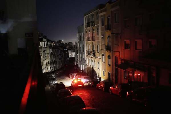 A car drives down an unlit street in Lisbon, during a nationwide power outage, Monday night, April 28, 2025. (AP Photo/Armando Franca)