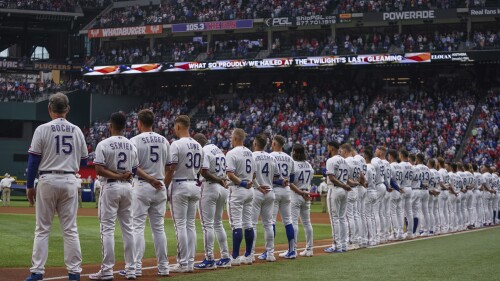 FILE - The Texas Rangers stand for the national anthem before an opening day baseball game against the Philadelphia Phillies, March 30, 2023, in Arlington, Texas. The Texas Rangers are the only one of the 30 MLB teams that aren't hosting Pride Night during a game in June as part of Pride Month. (AP Photo/Jeffrey McWhorter, File)