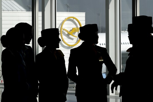 FILE - In this Thursday, March 16, 2017 file photo Lufthansa flight attendants silhouetted as they pose for a photograph on occasion of the company's annual press conference in Munich, Germany. Lufthansa and a union representing cabin crew reached a pay deal Thursday, concluding the last of several major disputes that have led to strikes recently at Germany's biggest airline and in the country's wider aviation sector. (AP Photo/Matthias Schrader,file)