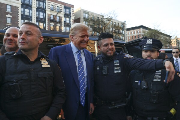 Former president Donald Trump, poses for a photo with New York Police officers after visiting a bodega, Tuesday, April 16, 2024, who's owner was attacked last year in New York. Fresh from a Manhattan courtroom, Donald Trump visited a New York bodega where a man was stabbed to death, a stark pivot for the former president as he juggles being a criminal defendant and the Republican challenger intent on blaming President Joe Biden for crime. Alba's attorney, Rich Cardinale, second from left, and Fransisco Marte, president of the Bodega Association, looked on. (AP Photo/Yuki Iwamura)