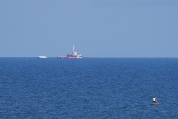 A ship belonging to the Open Arms aid group approaches the shores of Gaza towing a barge with 200 tons of humanitarian aid on Friday, March 15, 2024. (AP Photo/Abdel Kareem Hana)