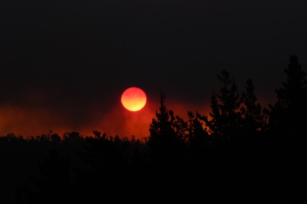The sun sets as smoke fills the sky during a the forest fire encroaching on Vina del Mar, Chile, Saturday, Feb. 3, 2024. (AP Photo/Esteban Felix)
