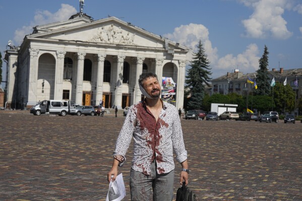 An injured man walks in Krasna square with the Taras Shevchenko Chernihiv Regional Academic Music and Drama Theatre in the background, after a Russian attack, in Chernihiv, Ukraine, Saturday, Aug. 19, 2023. (AP Photo/Efrem Lukatsky)