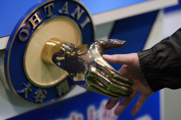 A visitor shakes hands with an iron model of Shohei Ohtani of the Los Angeles Dodgers, displayed at a local municipal government building in Oshu, northeastern Japan, the hometown of Ohtani, Tuesday, Oct. 29, 2024. (AP Photo/Eugene Hoshiko)