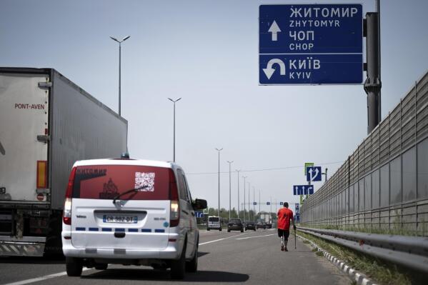 Serhii Khrapko, a Ukrainian war veteran, walks along a highway towards Zhytomyr, to meet his friend Oleksandr Shvetsov during a 120-kilometer (75-mile) walk to raise money for medical equipment in honor of their comrades wounded in Russia's war against their homeland in Motyzhyn, Ukraine, on Thursday, May 18, 2023. They raised 3.1 million hryvnias ($84,000), short just the 500,000 hryvnias ($14,000) needed to purchase a new gastroscope for Ukraine's National Military Medical Clinical Center. (AP Photo/Roman Hrytsyna)