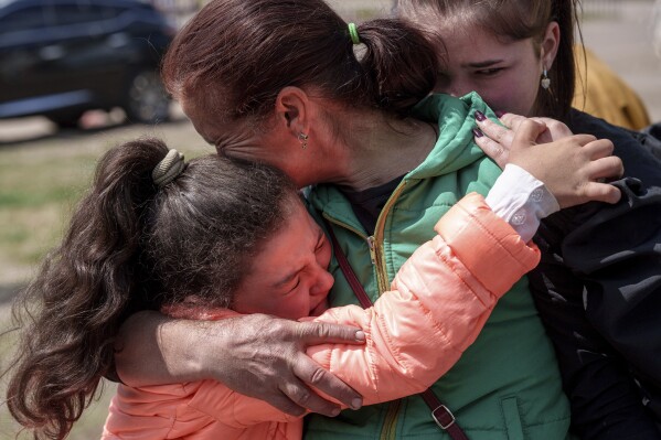 Khrystyna Pyimak, 11, hugs her mother Oksana Velychko, 42, after evacuation from Vovchansk, Ukraine, Sunday, May 12, 2024. (AP Photo/Evgeniy Maloletka)