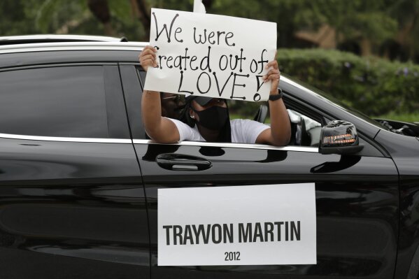FILE - In this June 3, 2020, file photo, people hold signs during a police escorted funeral procession organized by the COOL Church to symbolize a day of mourning for those lives lost due to systemic racism in Miramar, Fla. The Black Lives Matter movement emerged in 2013, its creators angered over the acquittal of Zimmerman. Several years since its founding, BLM has evolved well beyond the initial aspirations of its early supporters.(AP Photo/Lynne Sladky, File)