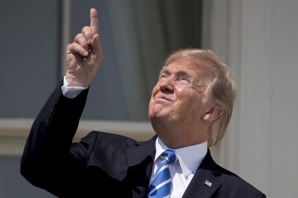 President Donald Trump points to the sun as he arrives to view the solar eclipse, Monday, Aug. 21, 2017, at the White House in Washington. (AP Photo/Andrew Harnik)