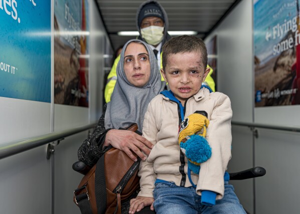 Four-year-old Omar Abu Kuwaik and his aunt Maha Abu Kuwaik, both from Gaza, are escorted through John F. Kennedy International Airport after departing a flight from Egypt on Wednesday, Jan. 17, 2024, in New York. Through the efforts of family and strangers, Omar was brought out of Gaza and to the United States, where he received treatment, including a prosthetic arm. (AP Photo/Peter K. Afriyie)