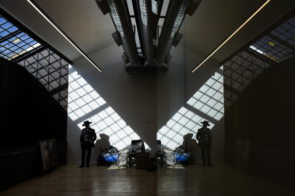 Enzo Restovic, reflected in a wall mirror on the right, takes a work break at “Donde Golpea el Monito” hat shop and museum, in Santiago, Chile, Thursday, April 3, 2025, that preserves a hat-making tradition dating back to 1915. (AP Photo/Esteban Felix)