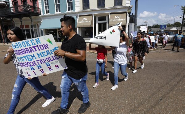 FILE - In this Aug. 11, 2019 photo, children of mainly Latino immigrant parents hold signs in support of them and those individuals picked up during an immigration raid at a food processing plant in Canton, Miss., following a Spanish Mass at Sacred Heart Catholic Church in Canton, Miss. Trump administration rules that could deny green cards to immigrants if they use Medicaid, food stamps, housing vouchers or other forms of public assistance are going into effect. (AP Photo/Rogelio V. Solis)