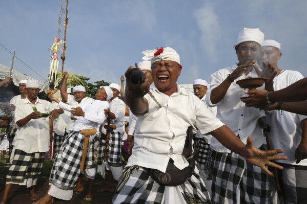 Devout Balinese Hindus enter into a trance and pierce themselves with metal swords while chanting prayers, on Melasti at Padanggala beach in Bali, Indonesia on Friday, March 8, 2024. Melasti is part of the six-day long Balinese Hindu New Year, where devout perform rituals as an act of symbolic cleansing. (AP Photo/Firdia Lisnawati)