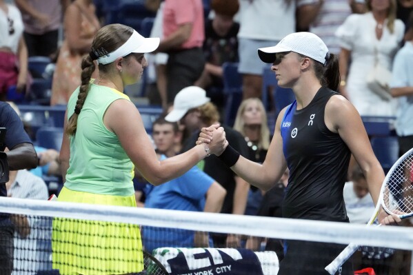 Jelena Ostapenko, of Latvia, left, shakes hands with Iga Swiatek, of Poland, at the end of the match, won by Ostapenko, in the fourth round of the U.S. Open tennis championships, Sunday, Sept. 3, 2023, in New York. (AP Photo/John Minchillo)