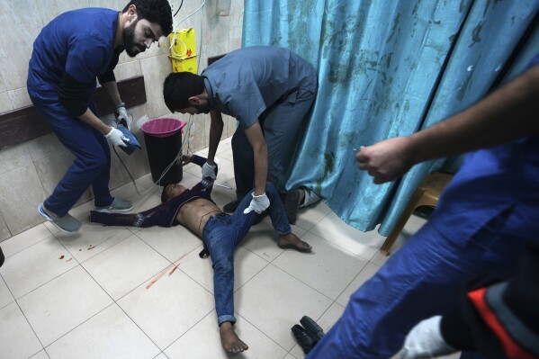 Palestinians wounded in the Israeli bombardment of the Gaza Strip are brought to a treatment room of al Aqsa Hospital on Deir al Balah, Gaza Strip, Friday, Nov. 10, 2023. (AP Photo/Adel Hana)