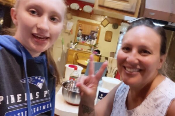 In this April 5, 2020, selfie provided by Amanda Reynolds, she and her mother Annette Reynolds pose for the photo at their home in Largo, Fla. The Florida teen recently marked her 18th birthday at home, obeying state guidelines and social-distancing rules, by making a cake with her mother and not celebrating with friends as she had planned. Amanda Reynolds is like all of these young people, a case study in what is being lost by those who, in spring 2020, are on the cusp of adulthood and losing many of their expected rites of passage. (Amanda Reynolds via AP)
