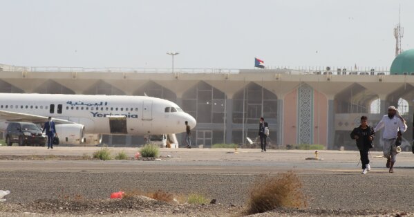 People walk away from the runway following an explosion at the airport in Aden, Yemen, shortly after a plane carrying the newly formed Cabinet landed on Wednesday, Dec. 30, 2020. No one on board the government plane was hurt but initial reports said several people at the airport were killed. (AP Photo/ Wael Qubady)