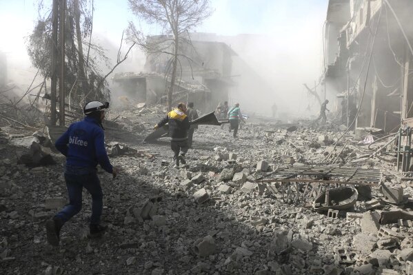 
              In this photo released on Tuesday Feb. 20, 2018 which provided by the Syrian Civil Defense group known as the White Helmets, shows members of the Syrian Civil Defense run to help survivors from a street that attacked by airstrikes and shelling of the Syrian government forces, in Ghouta, suburb of Damascus, Syria. A Syrian monitoring group and paramedics say government shelling and airstrikes on rebel-held suburbs of the capital, Damascus, killed at least 98 people on Monday. (Syrian Civil Defense White Helmets via AP)
            