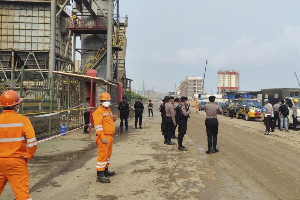 Police officers and workers stand near the site where a furnace explosion occurred at PT Indonesia Tsingshan Stainless Steel smelting plant in Morowali, Central Sulawesi, Indonesia, Sunday, Dec. 24, 2023. A smelting furnace has exploded at the Chinese-owned nickel plant on Indonesia's Sulawesi island, killing a number of workers and injuring dozens of others. The explosion on Sunday was the latest of a series of deadly accidents in nickel smelting plants in Indonesia that are part of China's ambitious transnational development program known as the Belt and Road Initiative. (AP Photo)