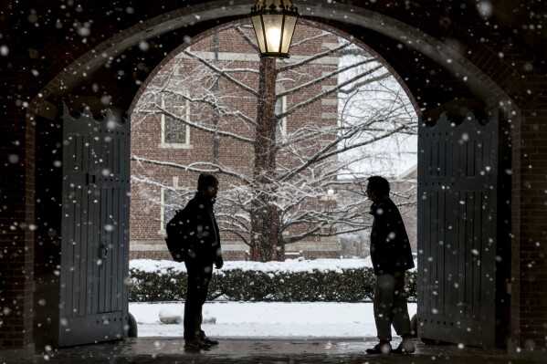 FILE - Wheaton College students stop to chat on the Norton, Mass. campus, Feb. 13, 2024 as snow falls. More than 75 million student loan borrowers have enrolled in the U.S. government's newest repayment plan since it launched in August. (Mark Stockwell/The Sun Chronicle via Ǻ, File)