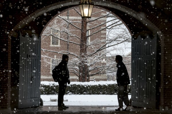 FILE - Wheaton College students stop to chat on the Norton, Mass. campus, Feb. 13, 2024 as snow falls. More than 75 million student loan borrowers have enrolled in the U.S. government's newest repayment plan since it launched in August. (Mark Stockwell/The Sun Chronicle via ĢӰԺ, File)