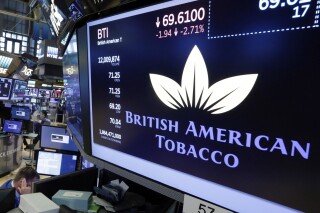 FILE - The logo for British American Tobacco appears above a trading post, July 24, 2017, on the floor of the New York Stock Exchange. Shares of British American Tobacco tumbled Wednesday, Dec. 6, 2023, after the owner of Camel and American Spirit cigarettes took an impairment charge of about $31.5 billion, mainly related to its struggling U.S. cigarette brands with the number of people who smoke in steep decline. (AP Photo/Richard Drew, File)