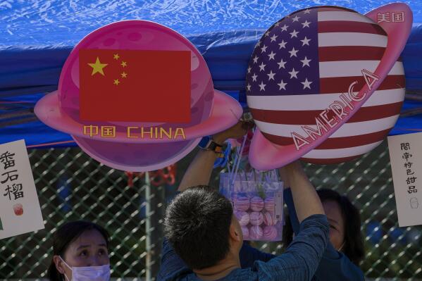 FILE - A vendor sets up foods and beverages at a booth displaying China and American flags during a Spring Carnival in Beijing, on May 13, 2023. China sentenced a 78-year-old United States citizen to life in prison Monday May 15, 2023 on spying charges, in a case that could exacerbate the deterioration in ties between Beijing and Washington over recent years. (AP Photo/Andy Wong, File)