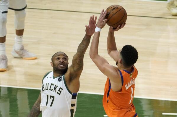FILE - Milwaukee Bucks forward P.J. Tucker (17) tries to block a shot by Phoenix Suns guard Devin Booker (1) during the second half of Game 4 of basketball's NBA Finals in Milwaukee, Wednesday, July 14, 2021. Veteran NBA forward P.J. Tucker signed with Miami this summer, a move that brings his flashy off-court style and his tough on-court ways to the Heat. (AP Photo/Paul Sancya, File)