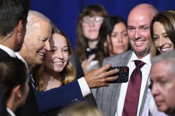 President Joe Biden takes a photo with Emma Kate Cox, daughter of Utah Gov. Spencer Cox, at the George E. Wahlen Department of Veterans Affairs Medical Center, Thursday, Aug. 10, 2023, in Salt Lake City. (AP Photo/Alex Goodlett)